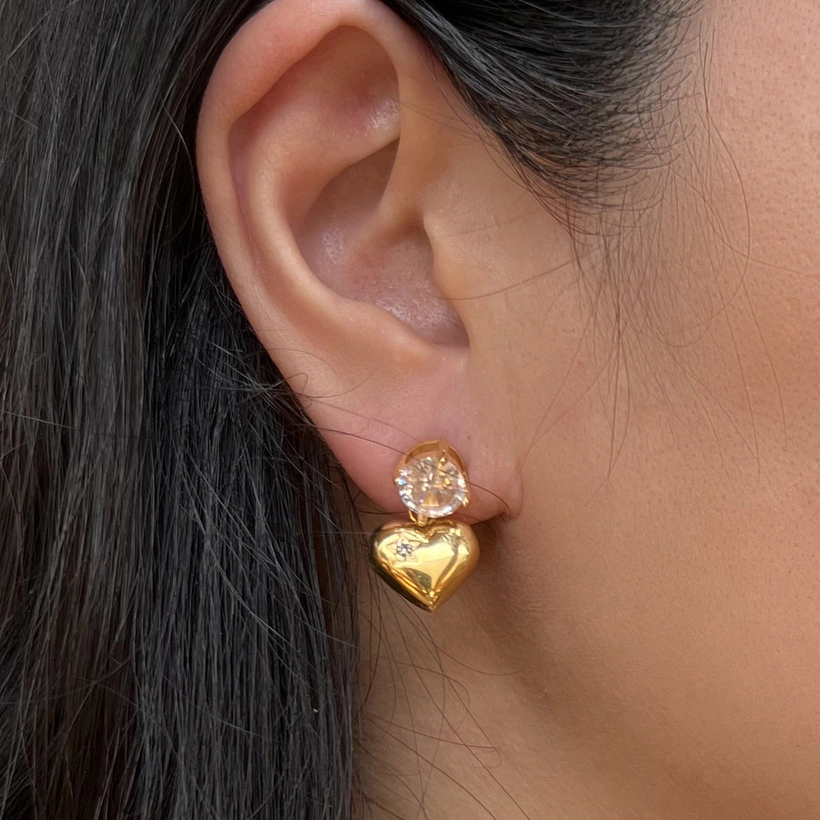 Boucles d’oreilles cœur scintillant dorées- Féerique Visée Bijoux, portées sur l'oreille d'une mannequin.