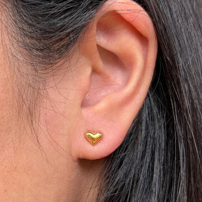 Boucles d'oreilles "Tendre discrétion" de Visée, en forme de cœur en acier doré, portées à l'oreille.