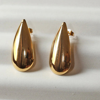 Boucles d'oreilles Larmes assumées en  acier doré, gouttes lumineuses capturées en gros plan.