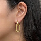 Boucles d'oreilles "J'existe" en acier doré, au design modulable, portées à l'oreille.