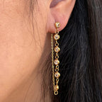 Boucles d'oreilles dorées Eclat en acier inoxydable, pendantes et serties de strass brillants. Vue portée à l'oreille.