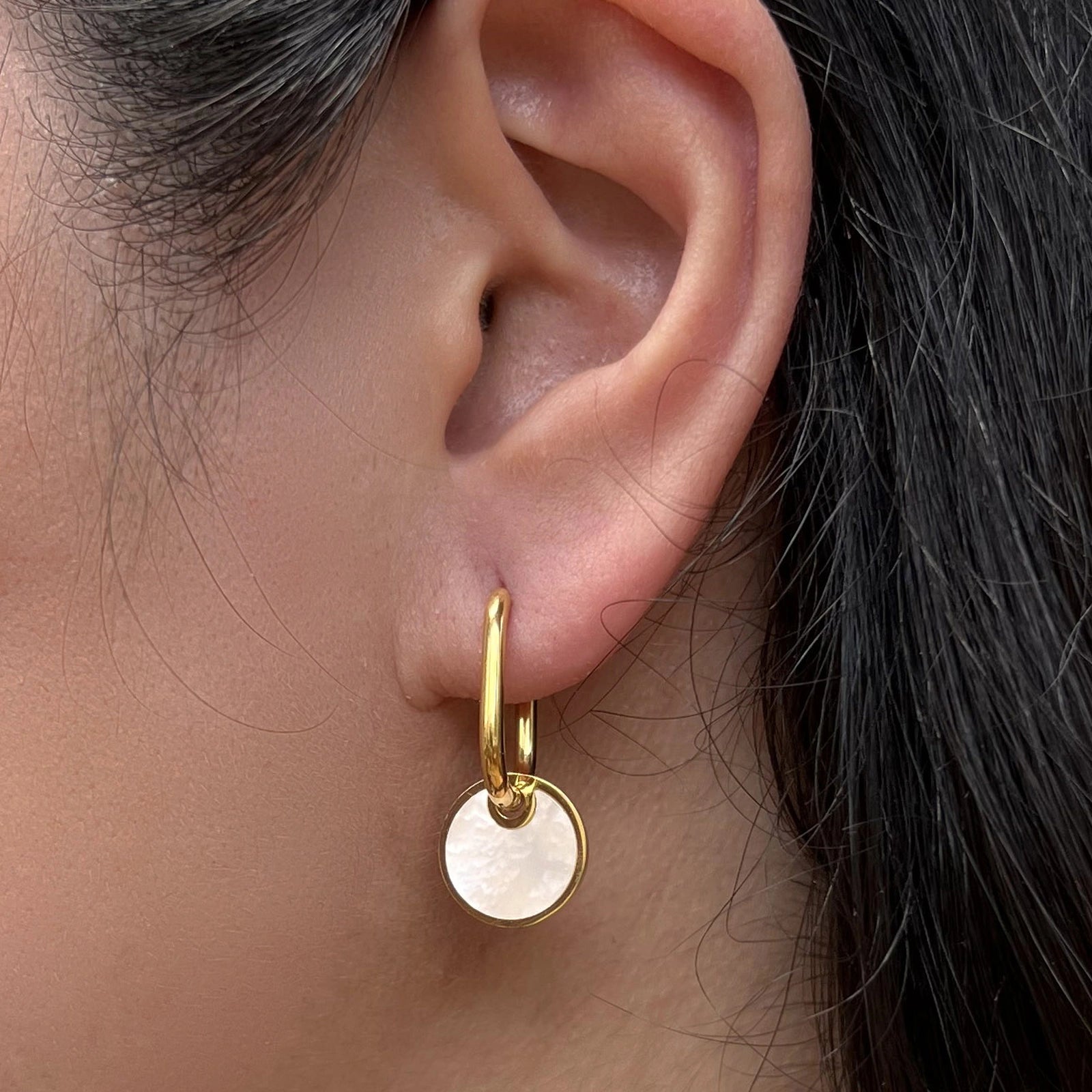 Boucles d'oreilles "Aude", en acier doré, pendentifs cercles personnalisables à effet nacré, portées à l'oreille.