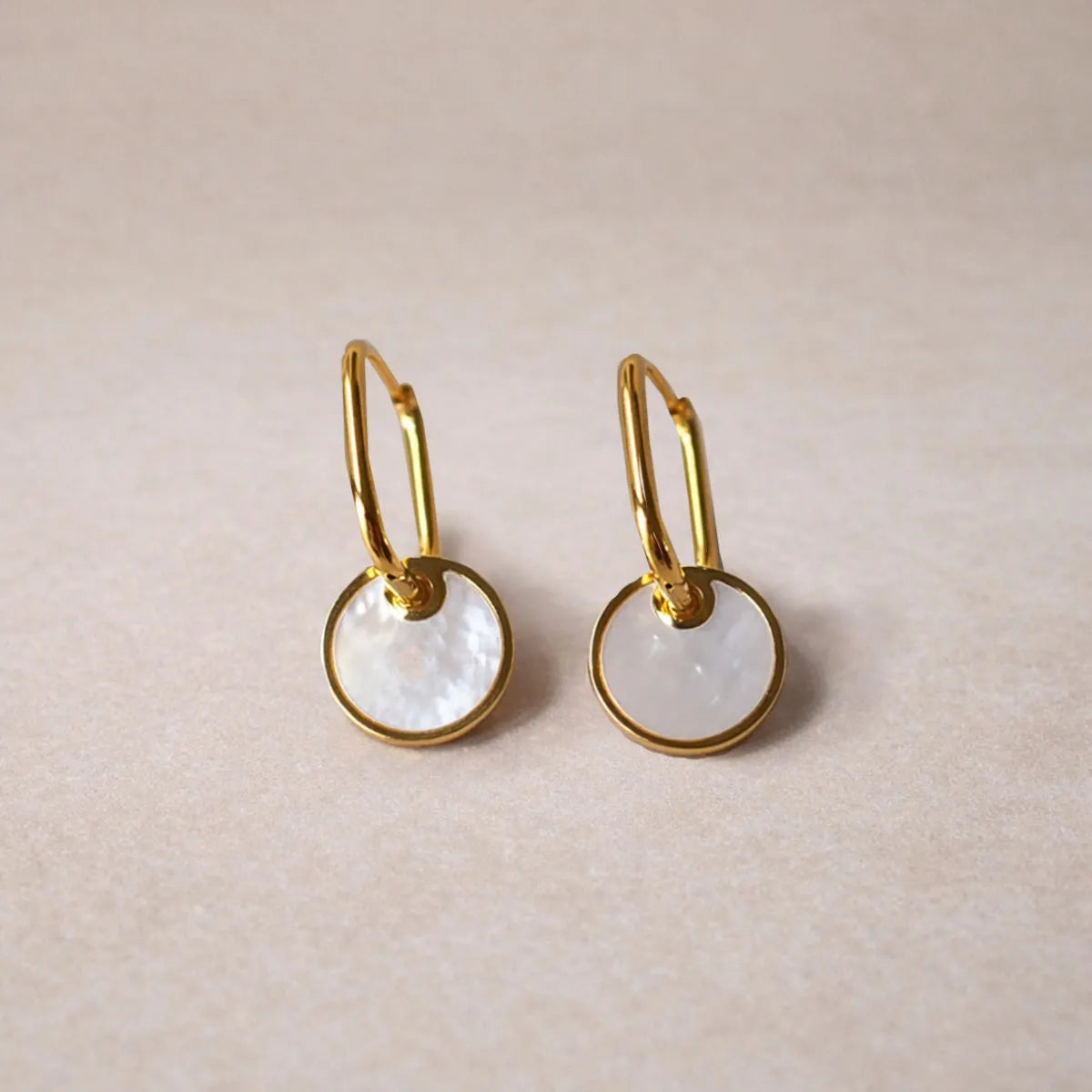 Boucles d’oreilles cercles – Aude Visée Bijoux, posé sur fond beige texturé