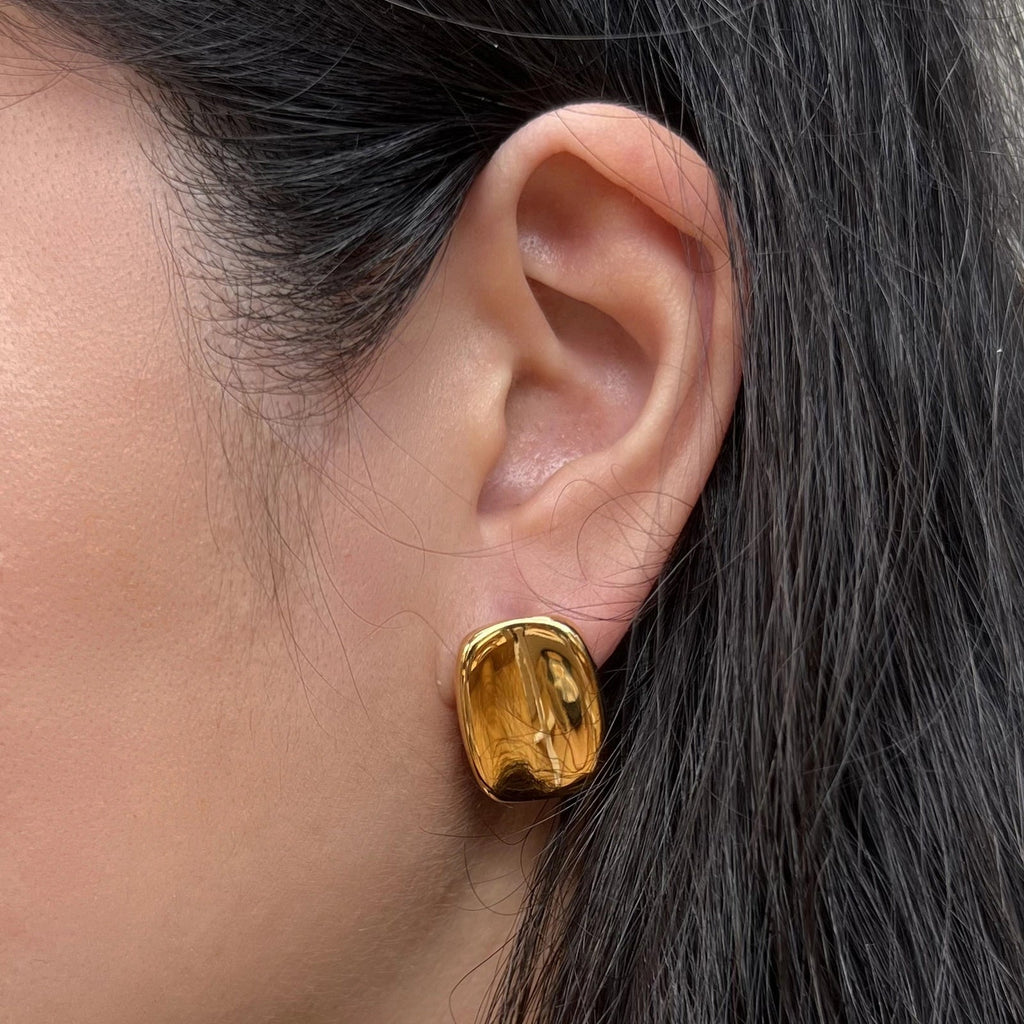 Boucles d’oreilles Fierté rectangulaires dorées minimalistes en acier inoxydable, portées à l'oreille, bijou signé Visée Bijoux.