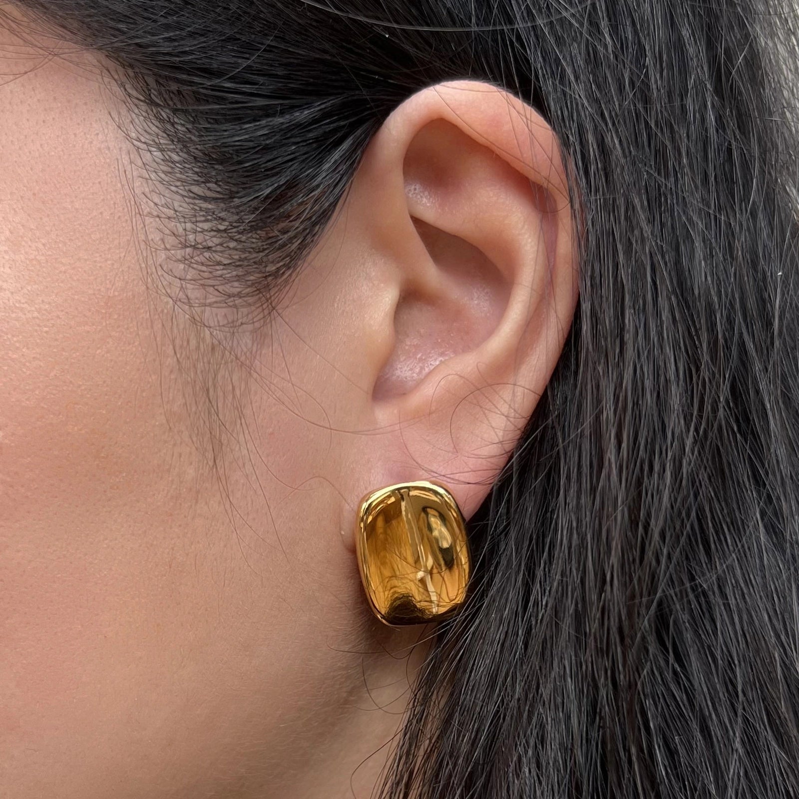 Boucles d’oreilles Fierté rectangulaires dorées minimalistes en acier inoxydable, portées à l'oreille, bijou signé Visée Bijoux.