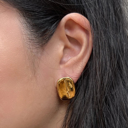 Boucles d’oreilles Fierté rectangulaires dorées minimalistes en acier inoxydable, portées à l'oreille, bijou signé Visée Bijoux.