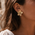 Boucles d’oreilles fleurs dorées- Fleurie Visée Bijoux, portées sur oreille de la mannequin, à la lumière naturelle du soleil. 