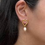 Boucles d’oreilles Loyale, en forme de cœur doré avec perle blanche, en acier inoxydable, portées sur une oreille - vue portée par Visée Bijoux.