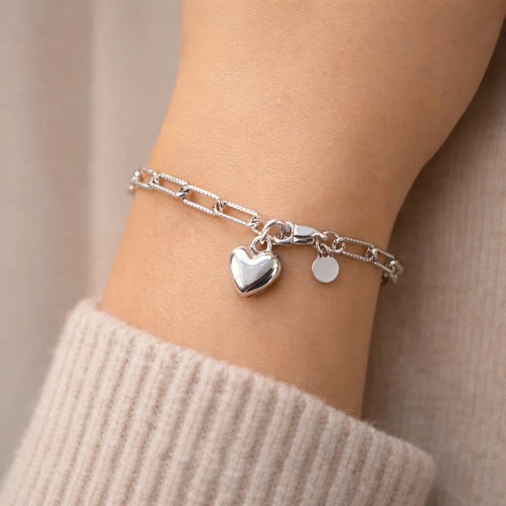 Bracelet Attache acier inoxydable argenté, avec breloque cœur personnalisable, porté au poignet.