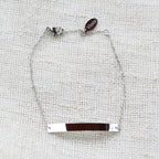 Bracelet gourmette "Sincérité" en acier inoxydable argenté,  personnalisable, posé sur un fond beige texturé.