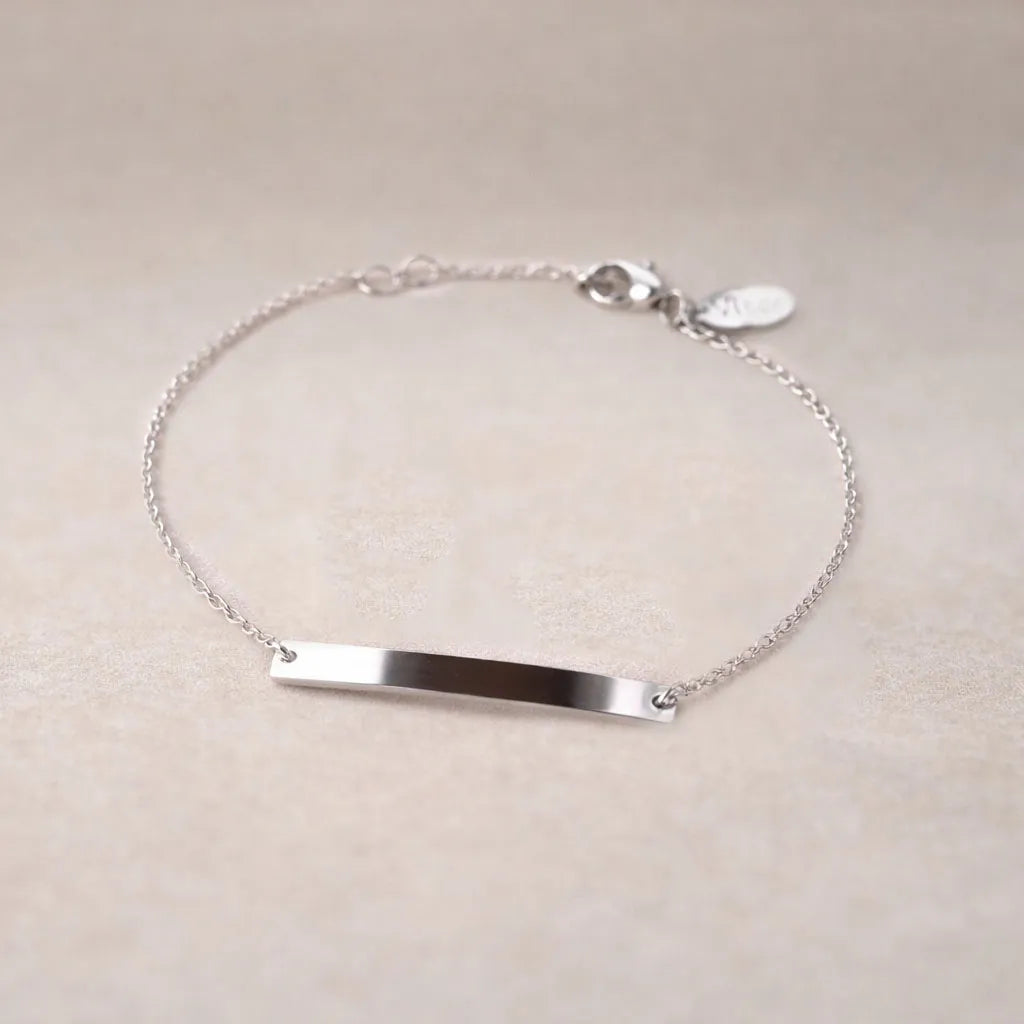 Bracelet gourmette "Sincérité" en acier inoxydable argenté,  personnalisable, posé sur un fond beige texturé.