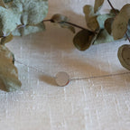 Bracelet "Confiance" en acier argenté personnalisable avec médaille ronde, présenté sur un tissu beige texturé. 