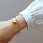 Bracelet Sans filtre en acier inoxydable doré, orné d'une breloque cœur personnalisée, délicatement porté au poignet.
