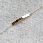 Bracelet gourmette "Sincérité" en acier inoxydable doré,  personnalisable, posé sur un fond beige texturé.