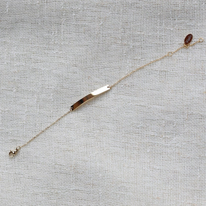 Bracelet gourmette "Sincérité" en acier inoxydable doré,  personnalisable, posé sur un fond beige texturé.