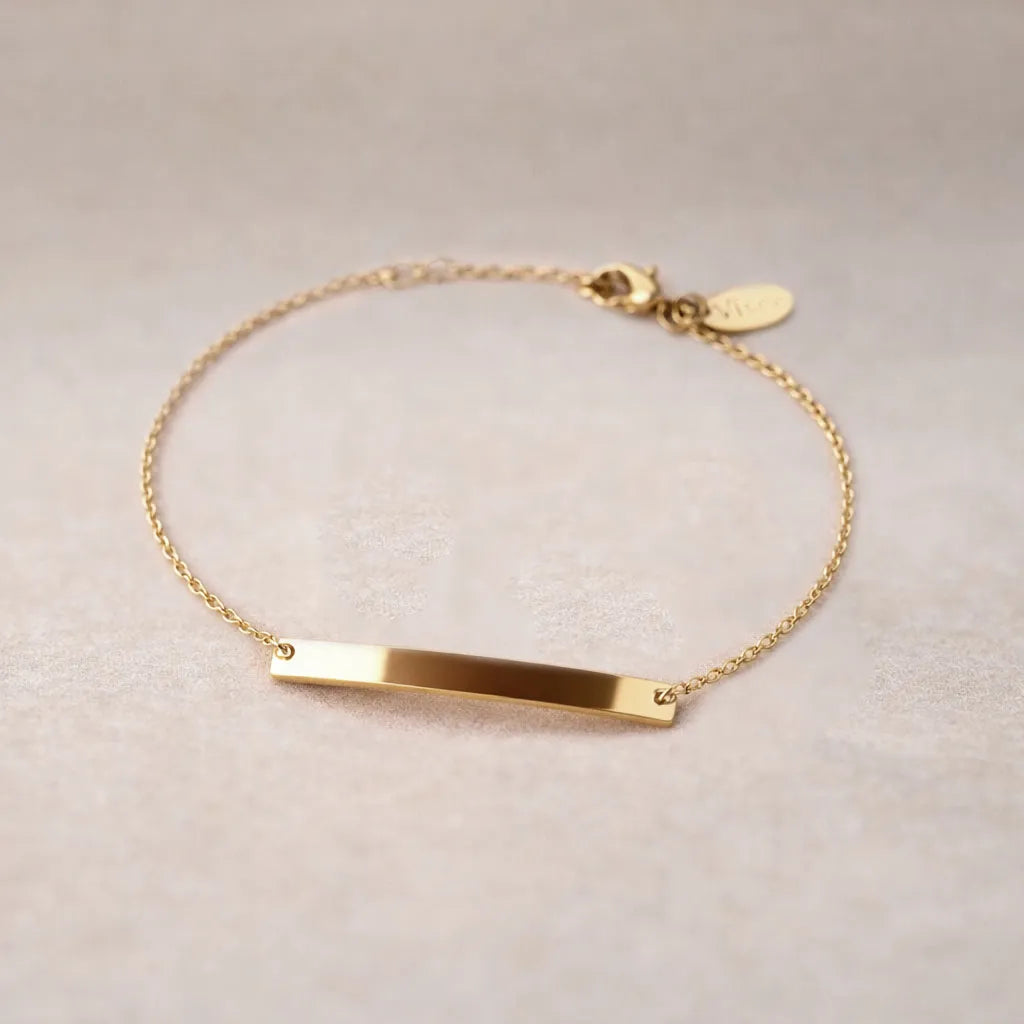 Bracelet gourmette "Sincérité" en acier inoxydable doré,  personnalisable, posé sur un fond beige texturé.