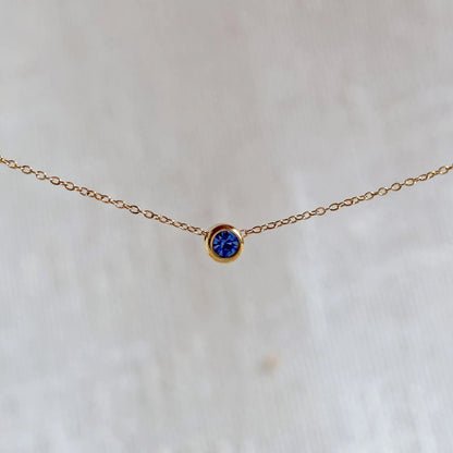Bracelet "Mon intérieur" en acier doré, orné d'une pierre bleue roi coulissante personnalisable, posé sur un fond beige.