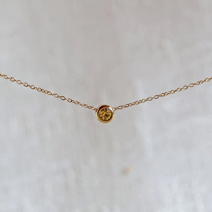 Bracelet "Mon intérieur" en acier doré, orné d'une pierre jaune coulissante personnalisable, posé sur un fond beige.