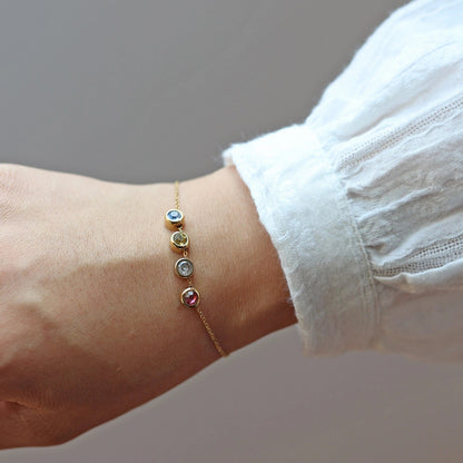 Bracelet "Mon intérieur" en acier doré, orné de pierres de couleurs coulissantes personnalisables, porté autour du poignet.