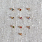 Pierres colorées en acier doré, posées sur un fond beige texturé.
