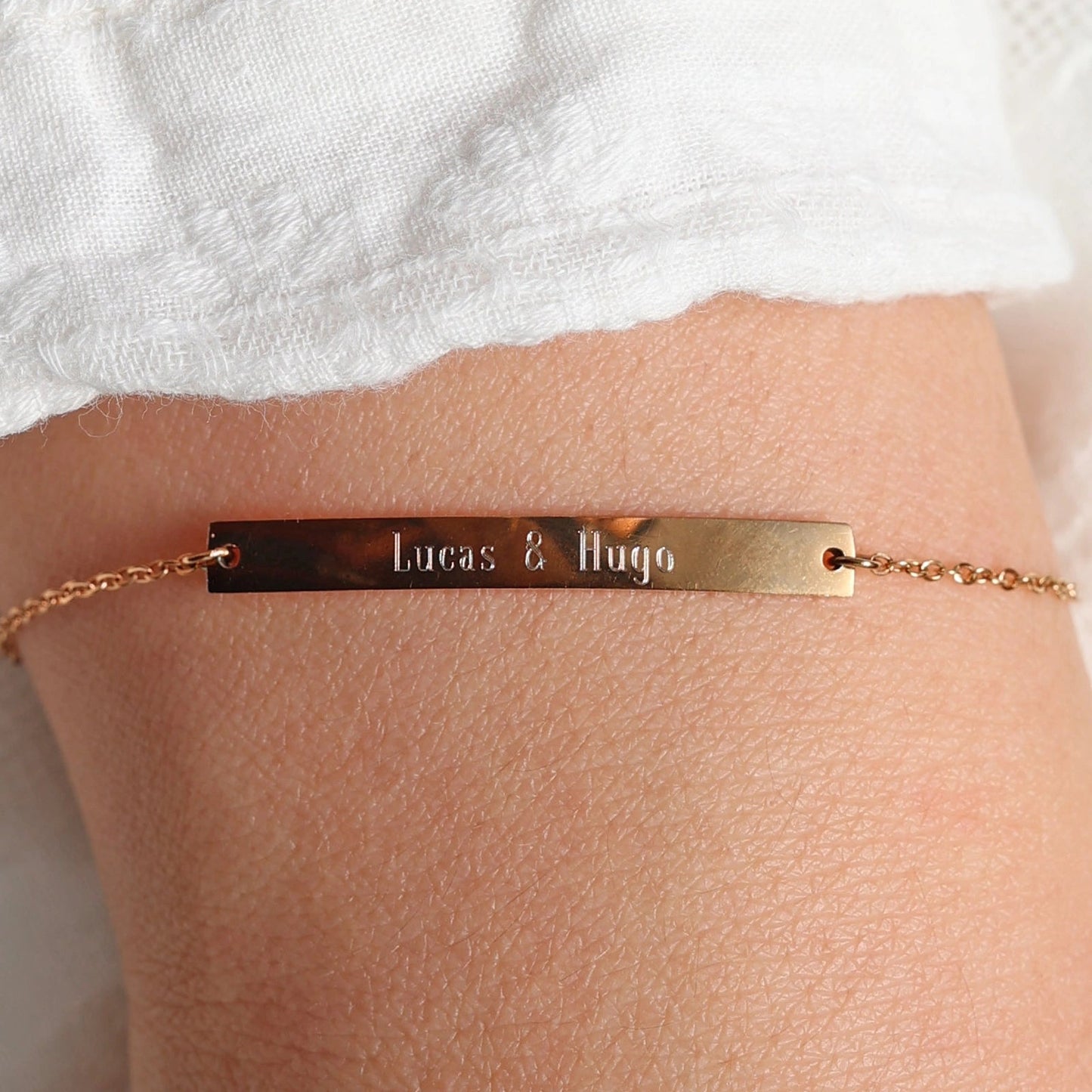 Bracelet gourmette "Sincérité" en acier inoxydable rosé,  personnalisé des noms "Lucas & Hugo", porté autour du poignet.