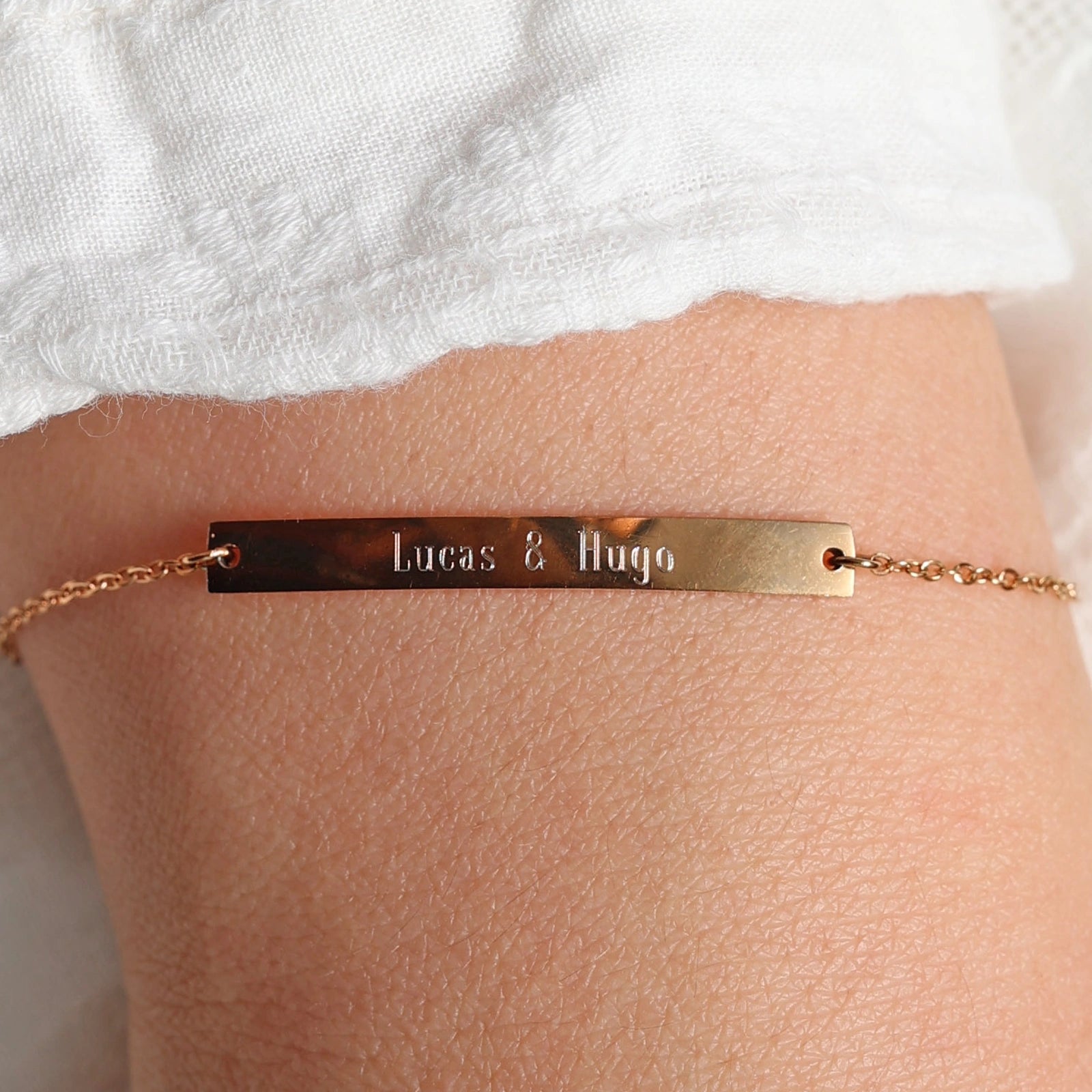 Bracelet gourmette "Sincérité" en acier inoxydable rosé,  personnalisé des noms "Lucas & Hugo", porté autour du poignet.