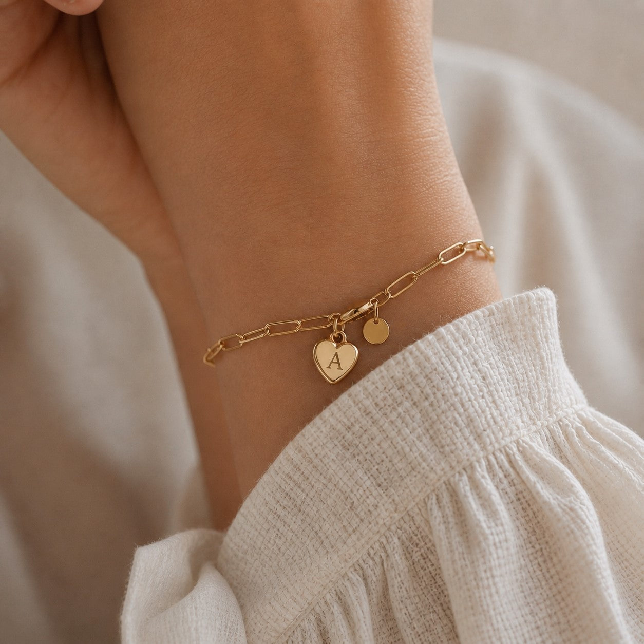 Bracelet chaîne paperclip breloque cœur gravé doré avec l'initiale , portée sur le poignet — Attache Visée Bijoux