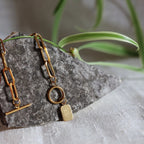 Zoom sur la breloque rectangulaire personnalisable en acier doré de dos, posé sur une pierre granite avec une feuille