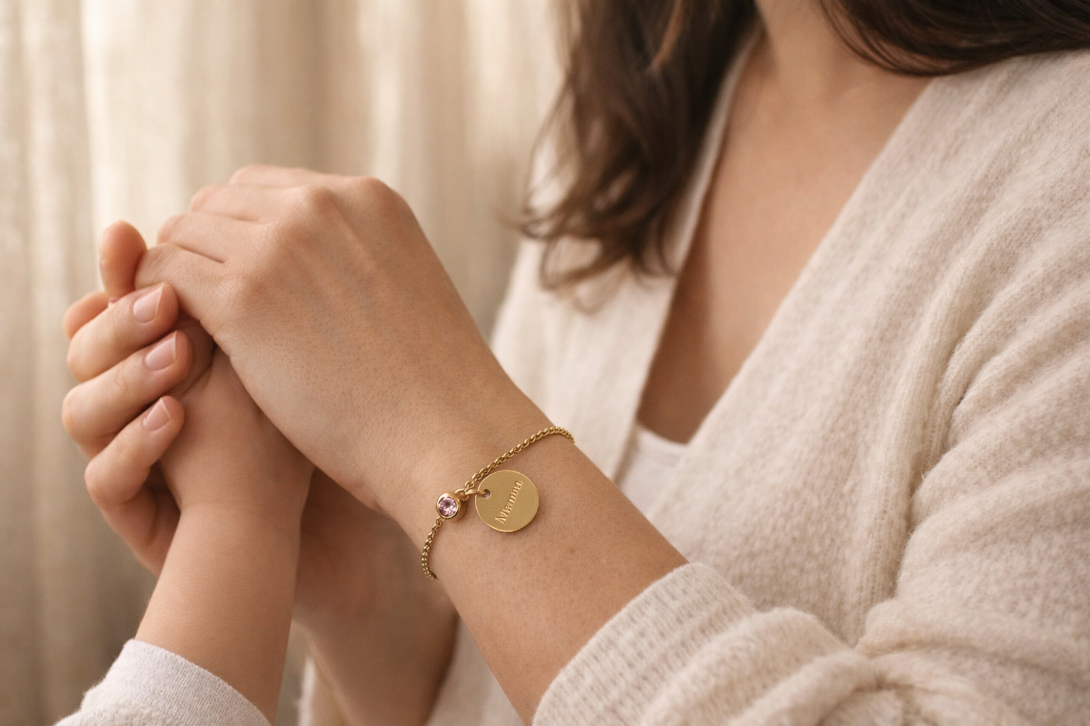 Bracelet doré personnalisé gravé "Maman" porté au poignet avec main d'enfant dans la main de maman— bijou Fête des Mères Visée Bijoux