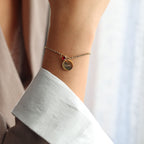 Bracelet Mon choix doré, bijou personnalisable en acier inoxydable avec médaillon gravé "Visée" et pierre de naissance rouge, porté au poignet.