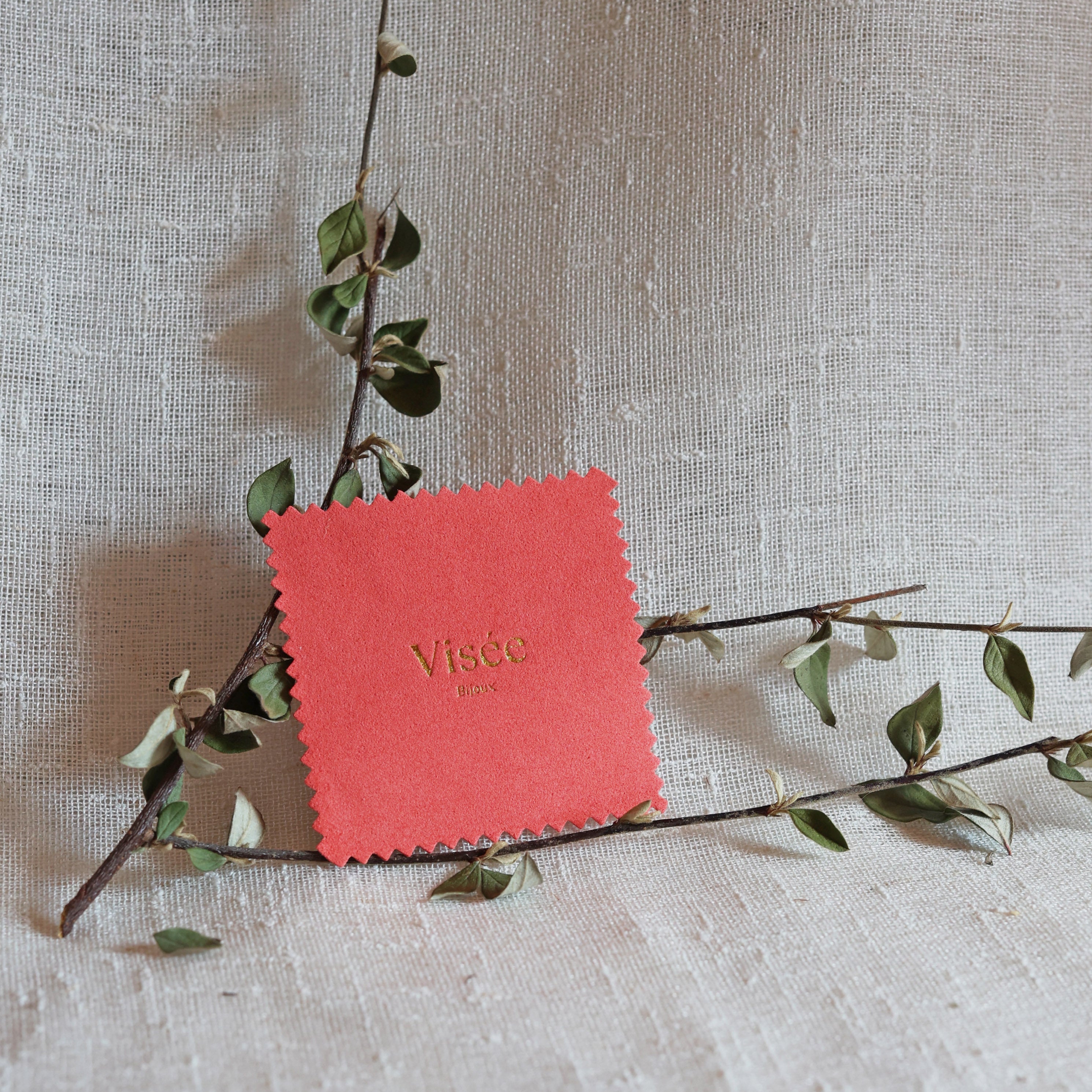 Chamoisine Visée en suédine corail, pour l'entretien délicat des bijoux, photographiée sur un fond beige.