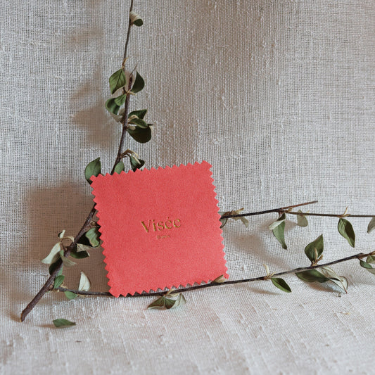 Chamoisine Visée en suédine corail, pour l'entretien délicat des bijoux, photographiée sur un fond beige.