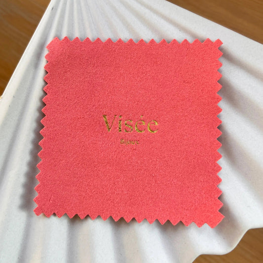 Chamoisine Visée en suédine corail, pour l'entretien délicat des bijoux, photographiée sur un fond beige.