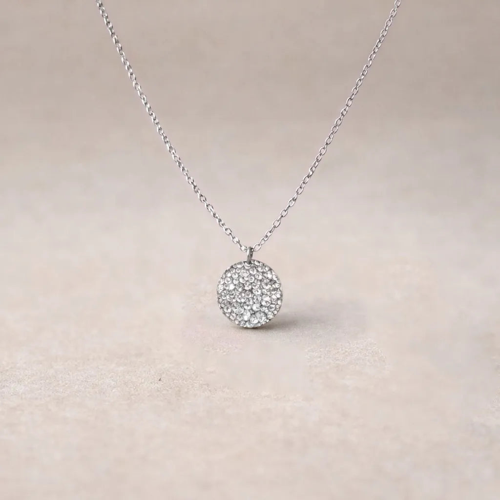 Collier Renaissance argenté, médaille ronde martelée à graver vue de face, posé sur fond beige texturé.