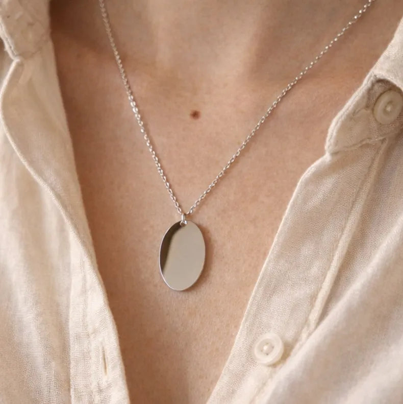 Zoom sur le collier "Tendresse", pendentif ovale personnalisable en acier inoxydable argenté, porté autour du cou.