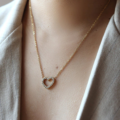 Collier Sentiment, avec pendentif cœur serti de brillants en acier inoxydable doré, porté autour du cou. 
