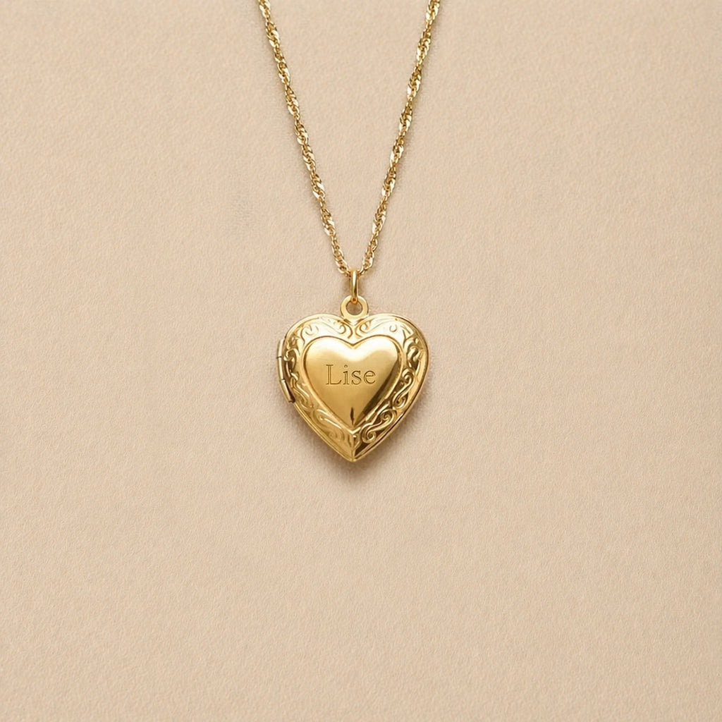 Zoom sur le collier Précieux, médaillon cœur en acier doré avec gravure et  photo souvenir à personnaliser, posé sur un fond beige texturé.