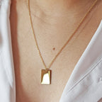 Collier "Je me souviens, en acier doré avec médaille rectangulaire à graver, porté autour du cou.