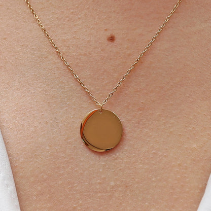 Collier "Reflet" avec médaille ronde personnalisé en acier inoxydable doré, porté autour du cou.