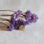 Collier Renaissance doré, médaille ronde martelée à graver vue de face, suspendue sur des fleurs violettes. 