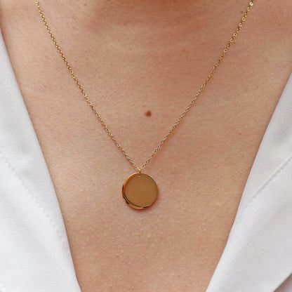 Collier "Reflet" avec médaille ronde personnalisé en acier inoxydable doré, porté autour du cou.
