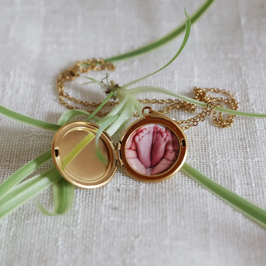 Collier "Ce jour là" avec médaillon rond personnalisable en acier doré, présenté sur un fond beige texturé.