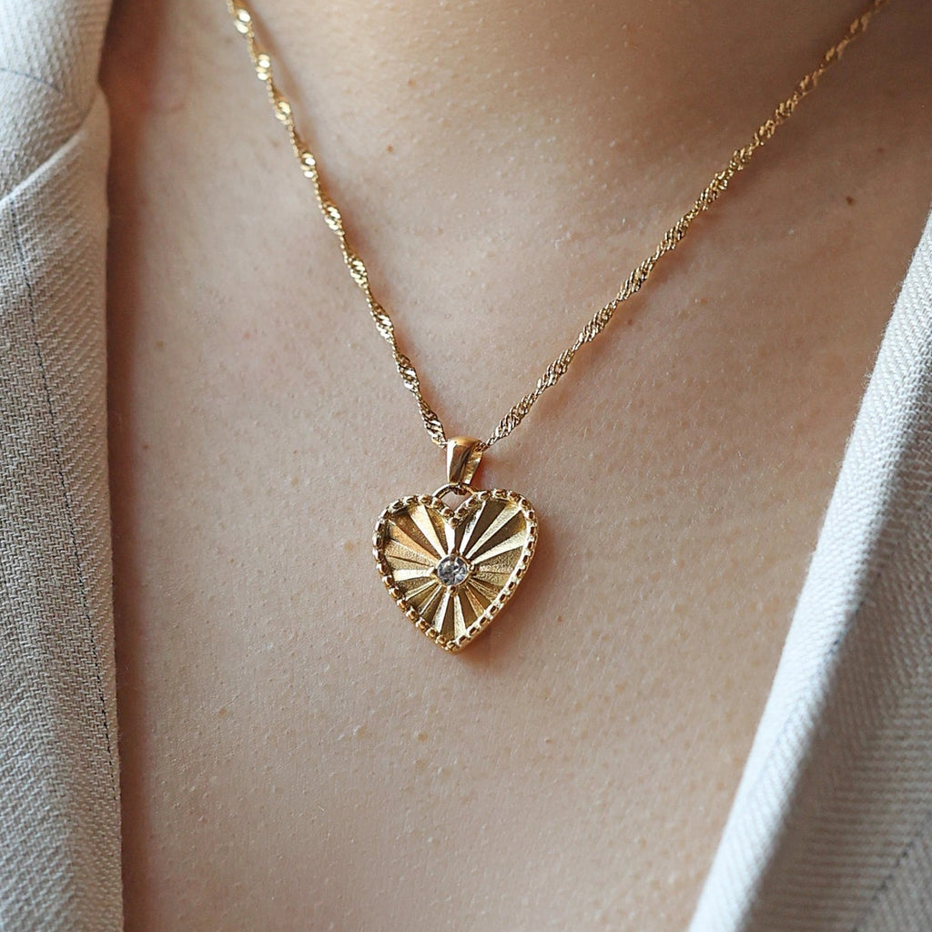 Collier Chérie en acier doré avec pendentif coeur strié orné d'un zircon central, personnalisable, porté autour du cou.