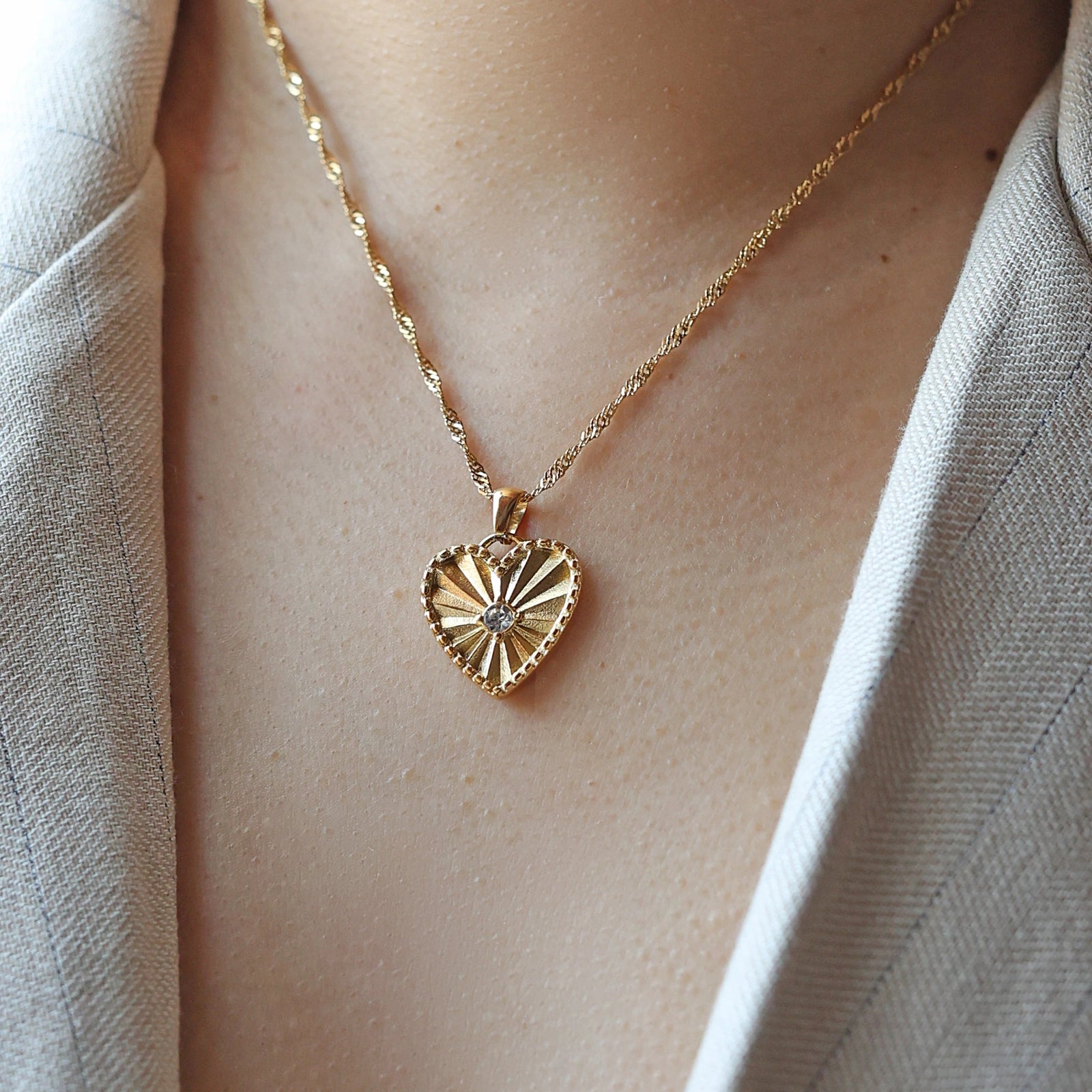 Collier Chérie en acier doré avec pendentif coeur strié orné d'un zircon central, personnalisable, porté autour du cou.