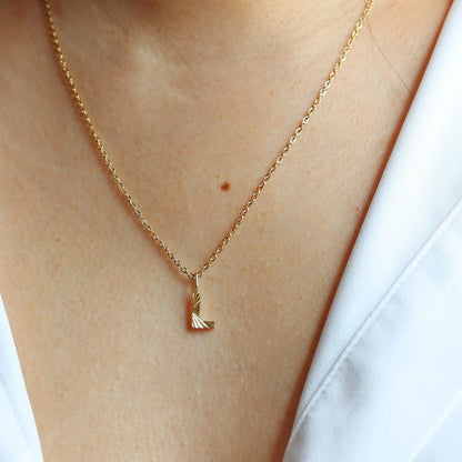 Collier "Je suis" avec pendentif lettre L striée, en acier doré, porté au cou.