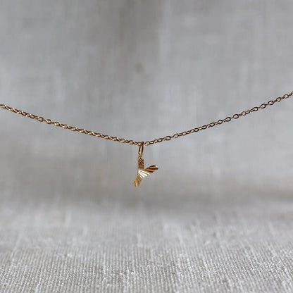 Collier "Je suis" avec pendentif lettre Y striée en acier doré, suspendu sur un fond en tissu beige texturé.