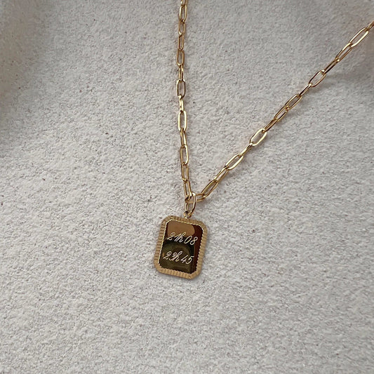 Collier "Ma vérité" avec pendentif rectangulaire personnalisable en acier doré, présenté sur un fond beige texturé.