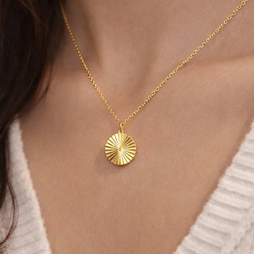 Collier "Energie" avec pendentif rond strié personnalisé en acier doré, porté autour du cou.