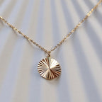 Zoom sur le collier "Energie" avec pendentif rond strié personnalisé en acier doré.