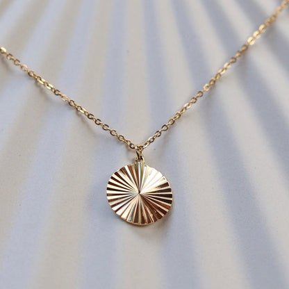 Zoom sur le collier "Energie" avec pendentif rond strié personnalisé en acier doré.